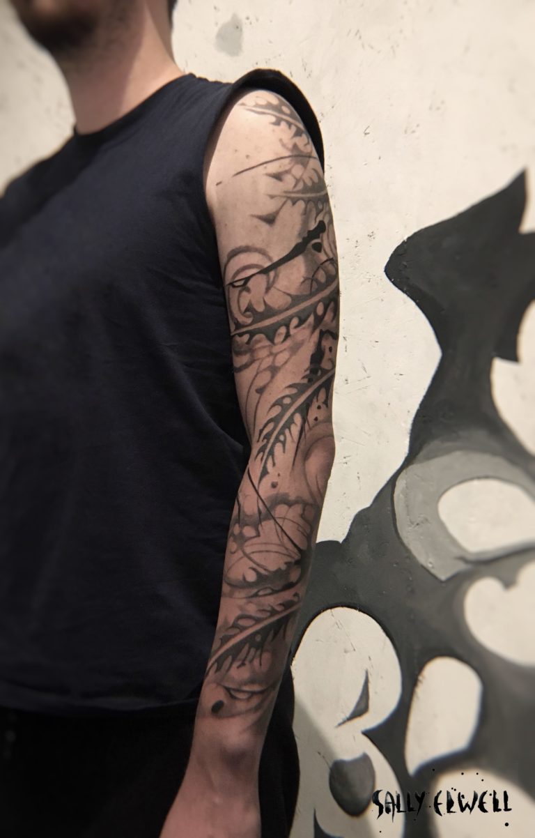 tatouage bras plumes formes abstraites dentelle organique encre noire et dégradés de gris