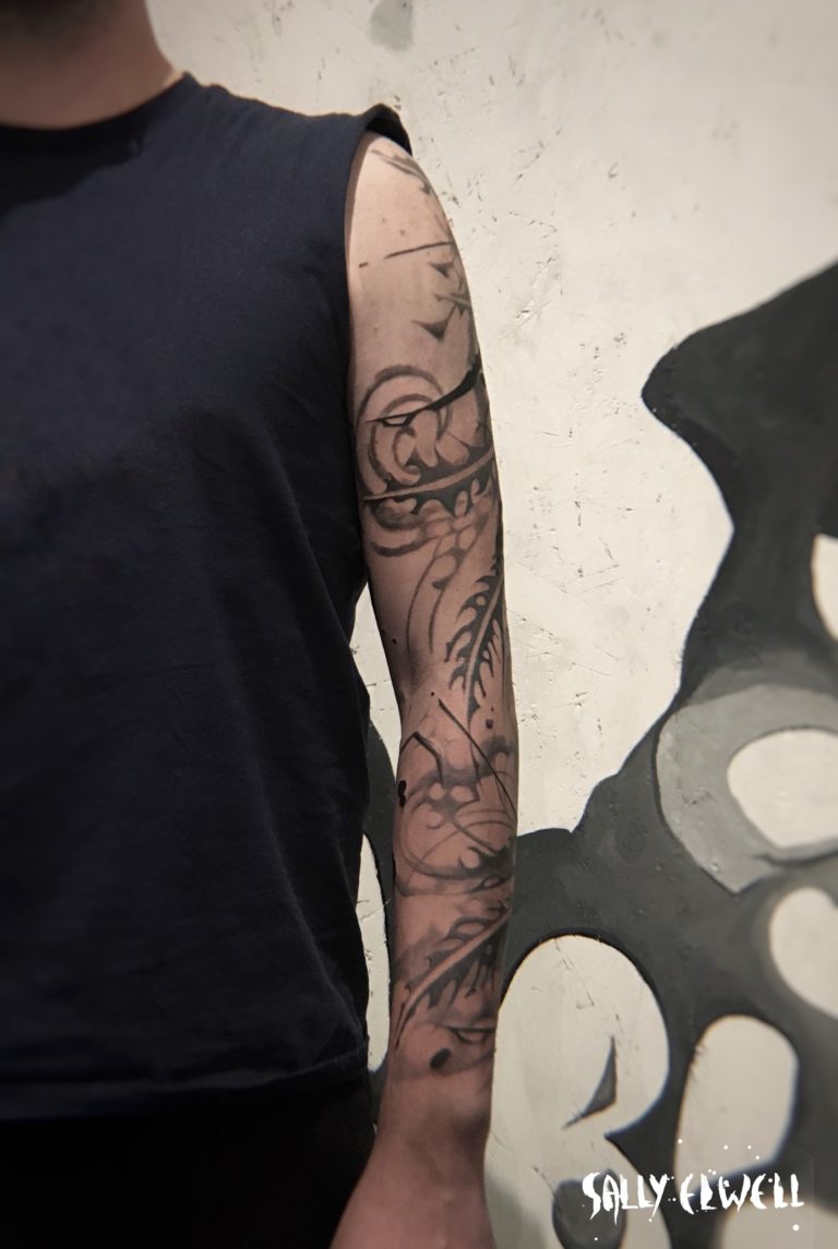 tatouage bras plumes formes abstraites dentelle organique encre noire et dégradés de gris