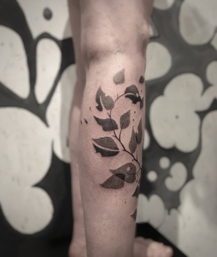 tatouage jambe branche feuillue profil