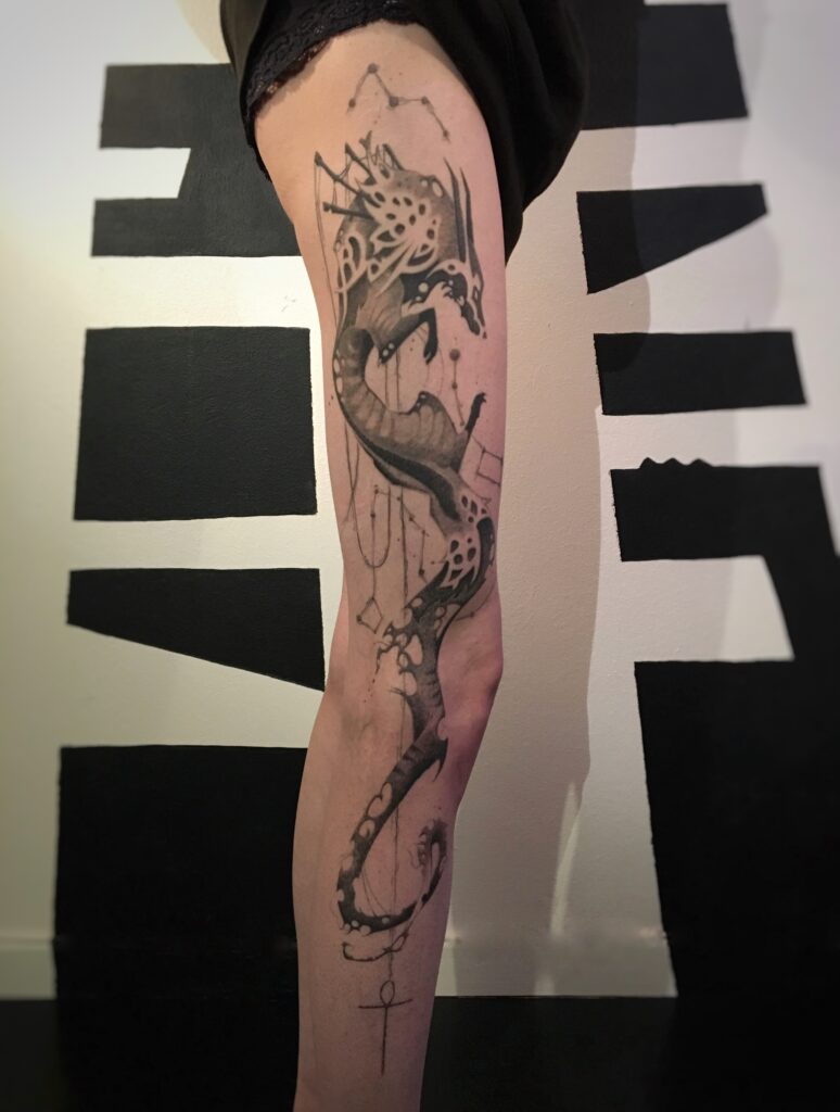 tatouage jambe entière dragon stylisé encore noire et dégradés de gris profil