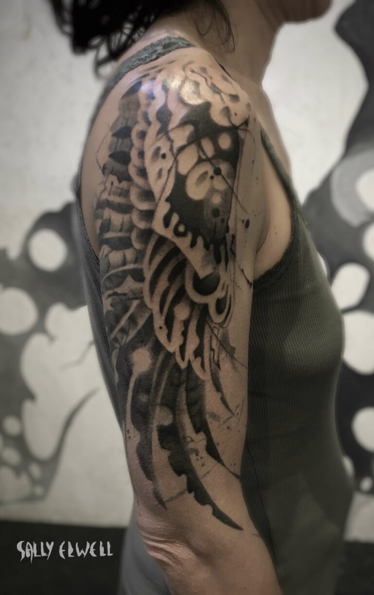 tatouage épaule bras ailes de buse encre noire et dégradé de gris tatouage épaule bras ailes de buse encre noire et dégradé de gris