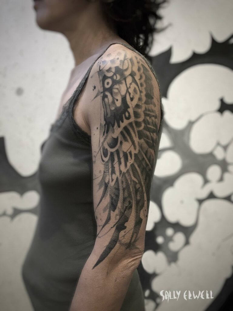 tatouage épaule bras ailes de buse encre noire et dégradé de gris tatouage épaule bras ailes de buse encre noire et dégradé de gris